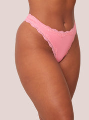 Pink lace thong worn by a person on a plain background