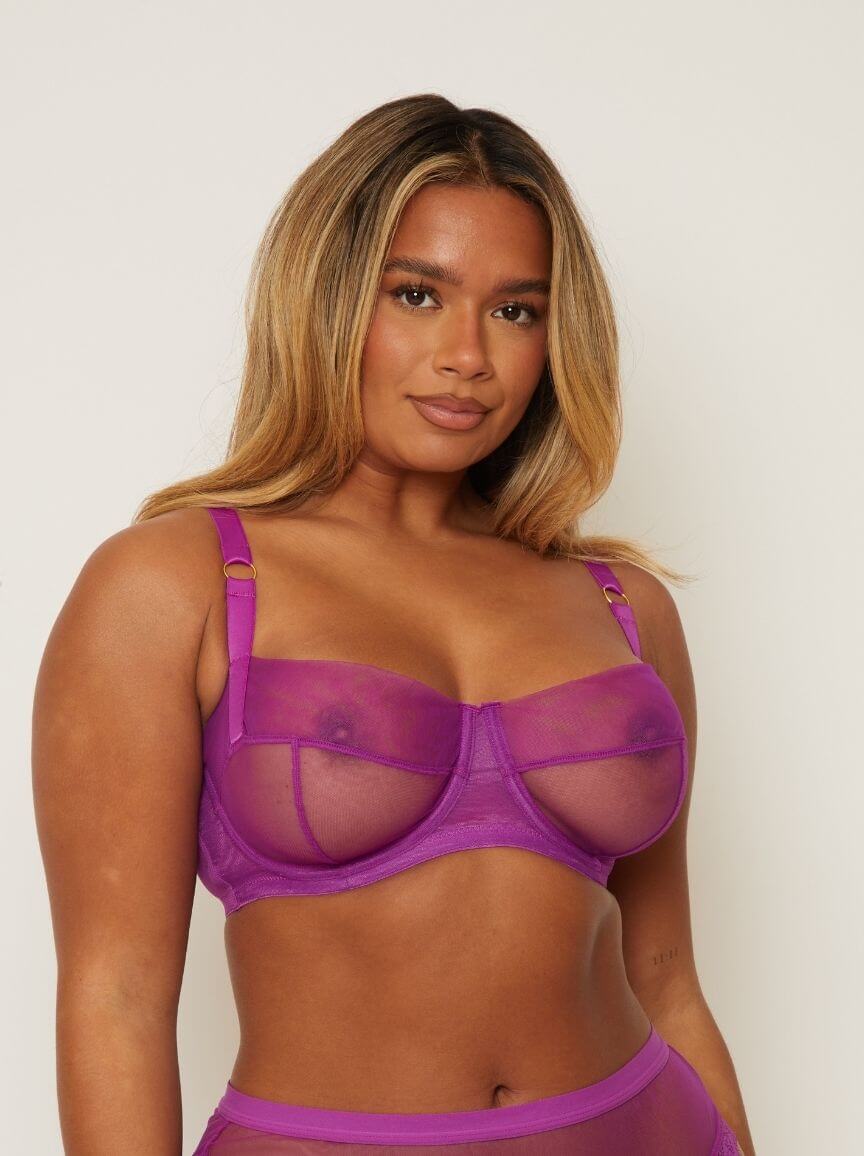Woman wearing a purple bra and panties set against a plain background